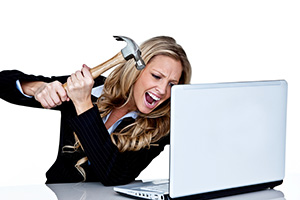 A woman is hammering her laptop with a hammer.