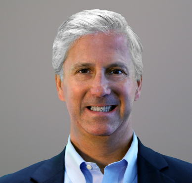 A man in a suit smiles for the camera.