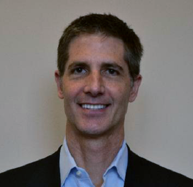 A man in a suit and tie smiling for the camera.