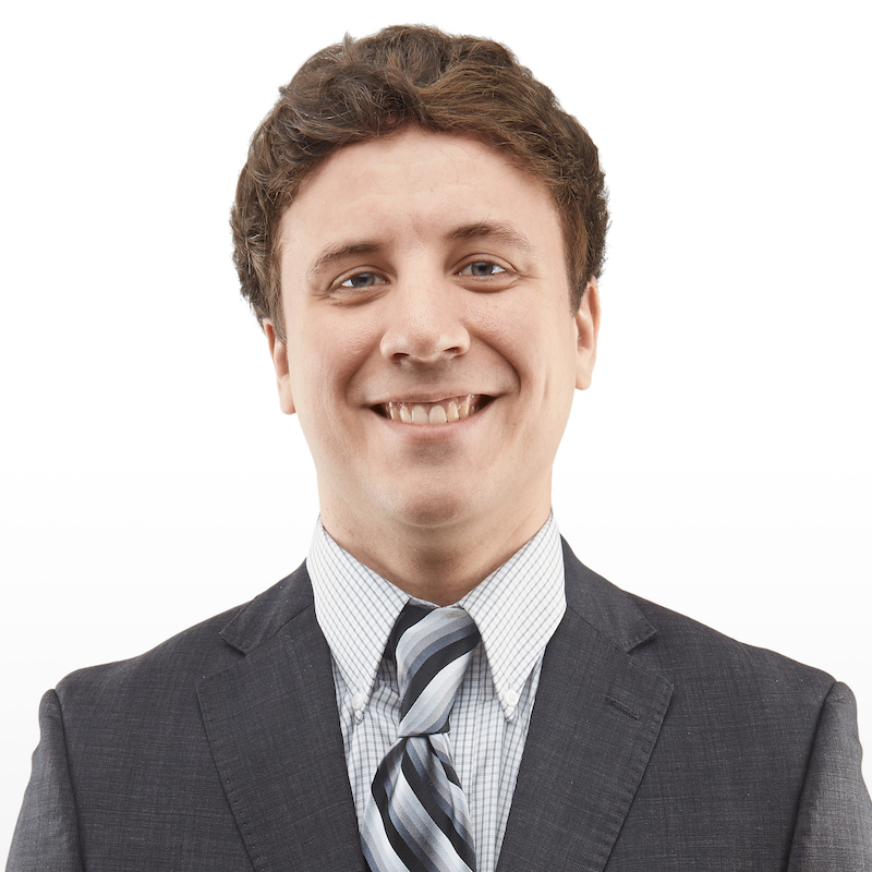 A man in a suit and tie smiling for the camera.